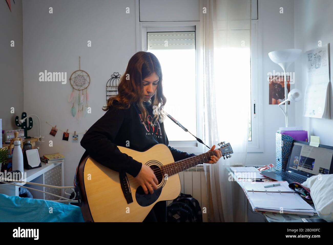 Teenager-Mädchen, das während der Covid19-Haft in Katalonien, Spanien, Gitarre in ihrem Schlafzimmer spielt Stockfoto