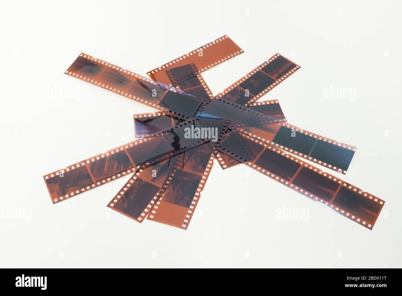 So viele Streifen von fotografischen Negativen, die zufällig auf einem weißen Hintergrund angeordnet sind. Stockfoto