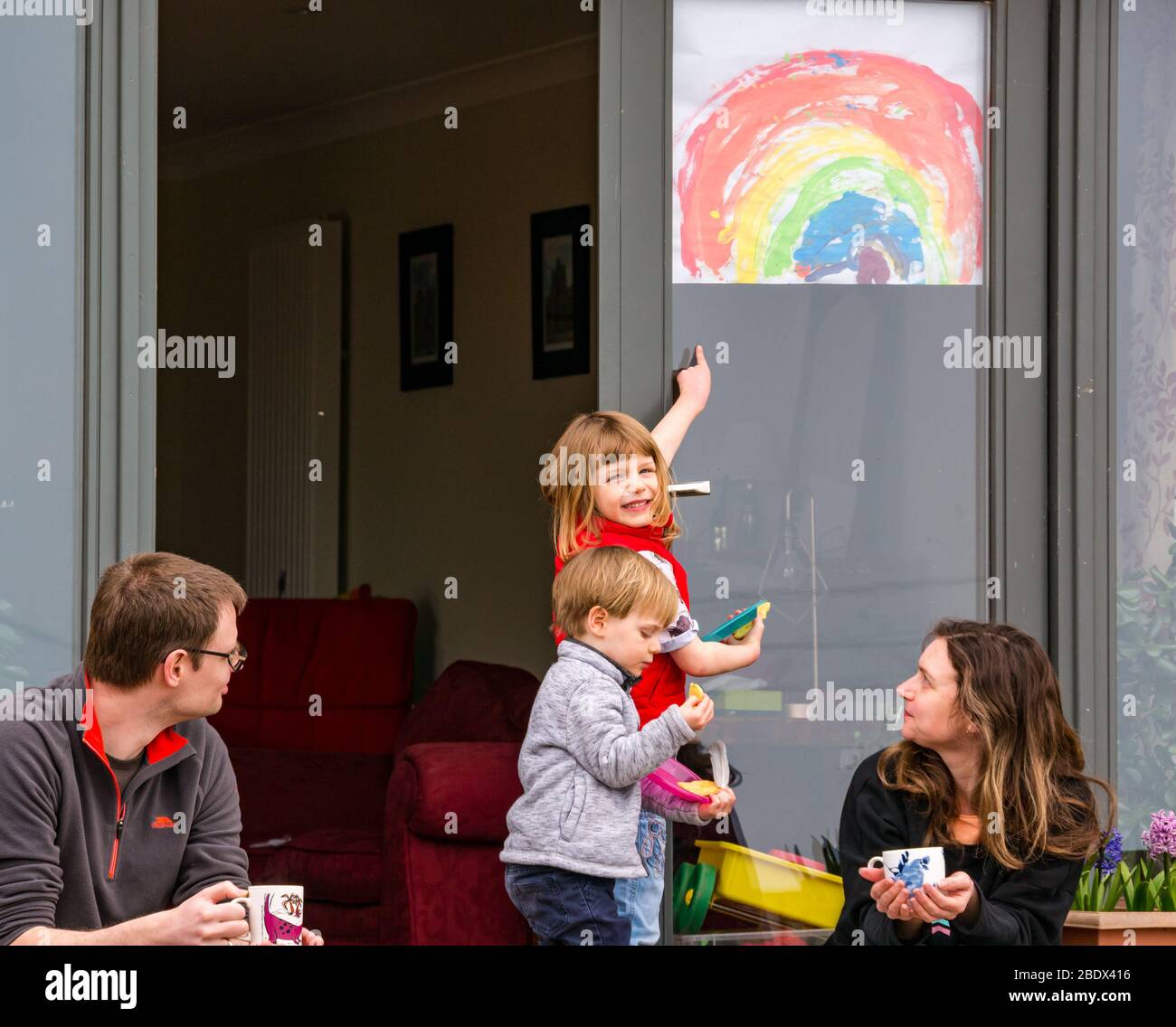 East Lothian, Schottland, Großbritannien. April 2020. Covid-19 Lockdown: Eine Regenbogenzeichnung der Hoffnung eines Kindes in einem Hausfenster gezeichnet von Alice Whiteley, 5 Jahre alt. Die Familie Whiteley genießt das Osterwochenende vor ihrer Haustür während der Coronavirus-Pandemie mit ihren Kindern Toby (2 Jahre alt) und Alice Stockfoto