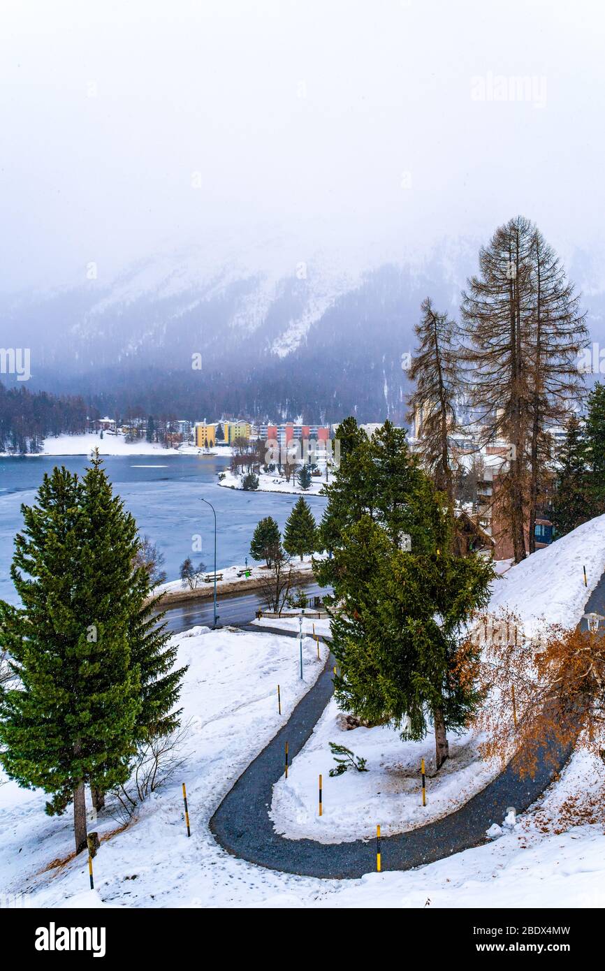 Saint Moritz, Schweiz - 20. Dezember 2019 - kleine kurvenreiche Straße führt bei kaltem Schnee zum gefrorenen St. Moritzersee in Saint Moritz, Schweiz Stockfoto