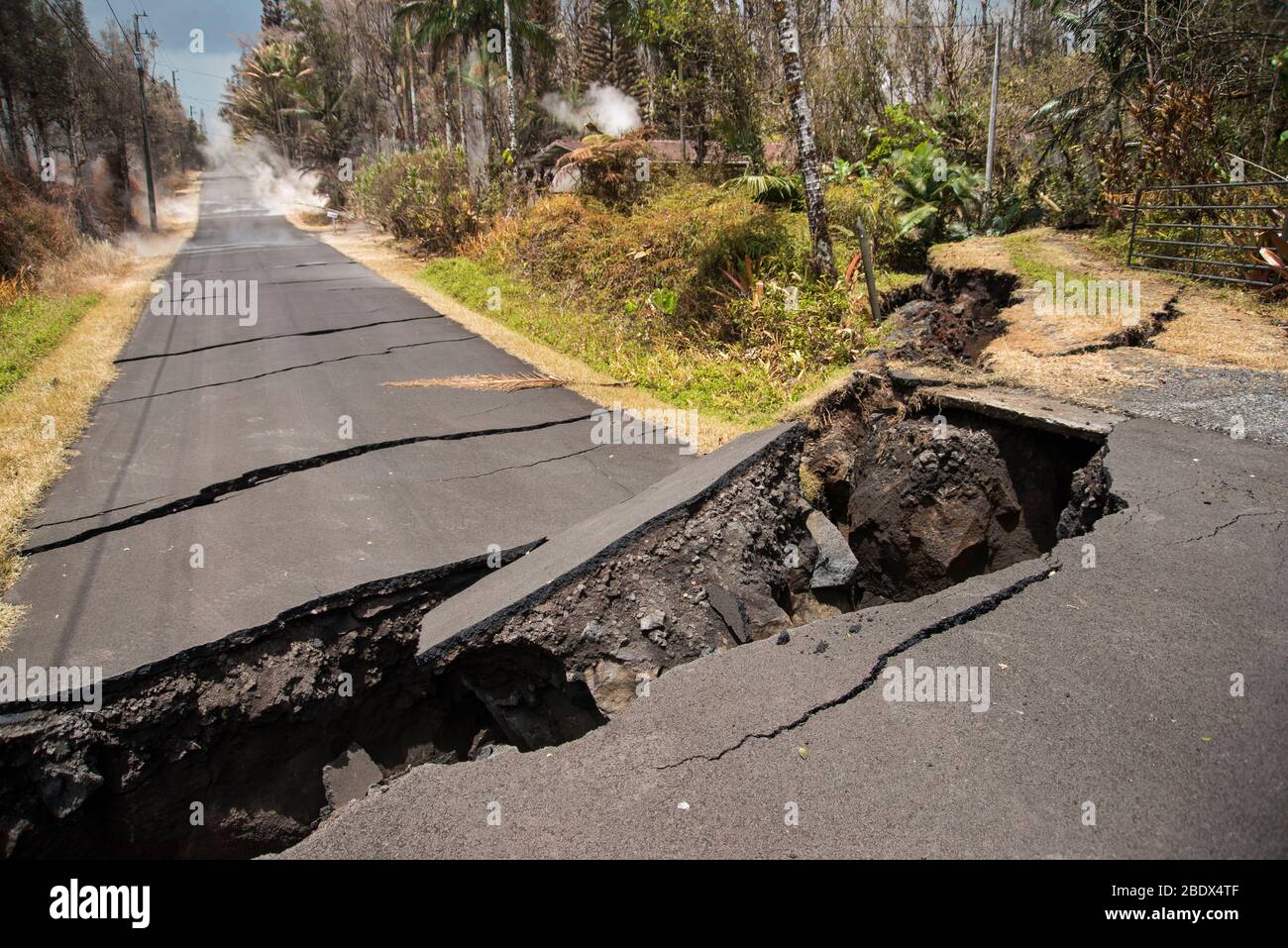 Straße, die von einem von mehreren Erdbeben während der Vulkanausbruch Kīlauea betroffen, was einen 80-Fuß-Drop in den Boden. Beachten Sie die Gase, die von den Rissen im Asphalt, weiter die Straße hinunter. Bild aufgenommen am 19. Mai 2018. Stockfoto