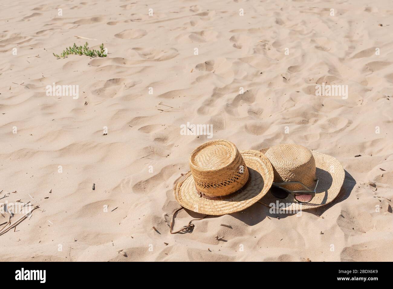 Blick auf den sandigen Strand mit Sommerhüten und Sonnenbrille. Leere Werbung oder Verpackungslayout. Stockfoto