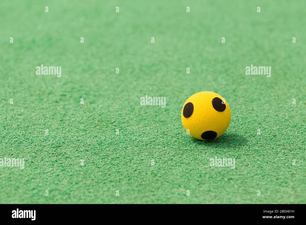 Einzelne gelbe Kugel auf grünen AstroTurf bei Kent Schulspielen. Stockfoto
