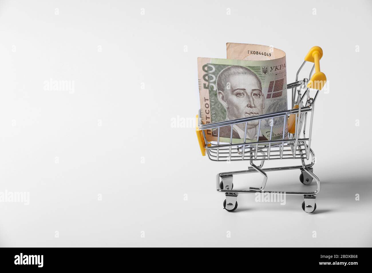 Banknote ukrainischen Griwna in den Warenkorb auf Shopping isoliert auf weißem Hintergrund. Nahaufnahme von Shopping-Trolley. Business-Konzept mit Kopie Stockfoto
