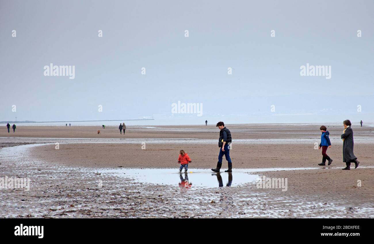 Portobello Beach, Edinburgh, Schottland, Großbritannien. April 2020. Abgebildet: Nebliger Morgen, der den Bildern einen fast monochromen Blick verleiht. Menschen bleiben weit voneinander entfernt, so körperliche soziale Distanzierung und ein Hund, der scheint seine Zunge heraus auf den Fotografen am Sandstrand mit der Flut weit draußen zu stecken. Quelle: Arch White / Alamy Live News. Stockfoto