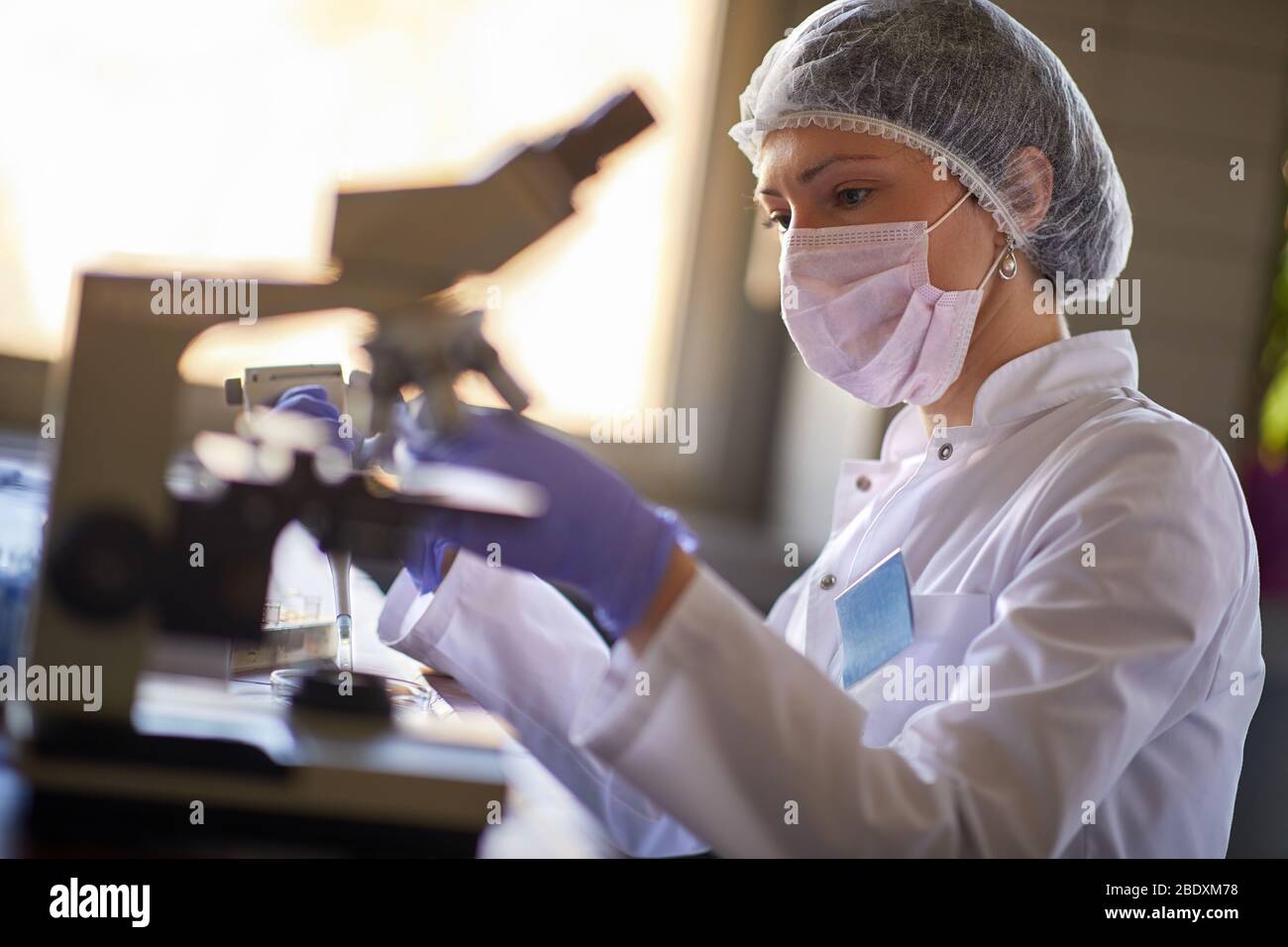 Laborarbeiterin, die durch das Mikroskop Blut sucht Stockfoto