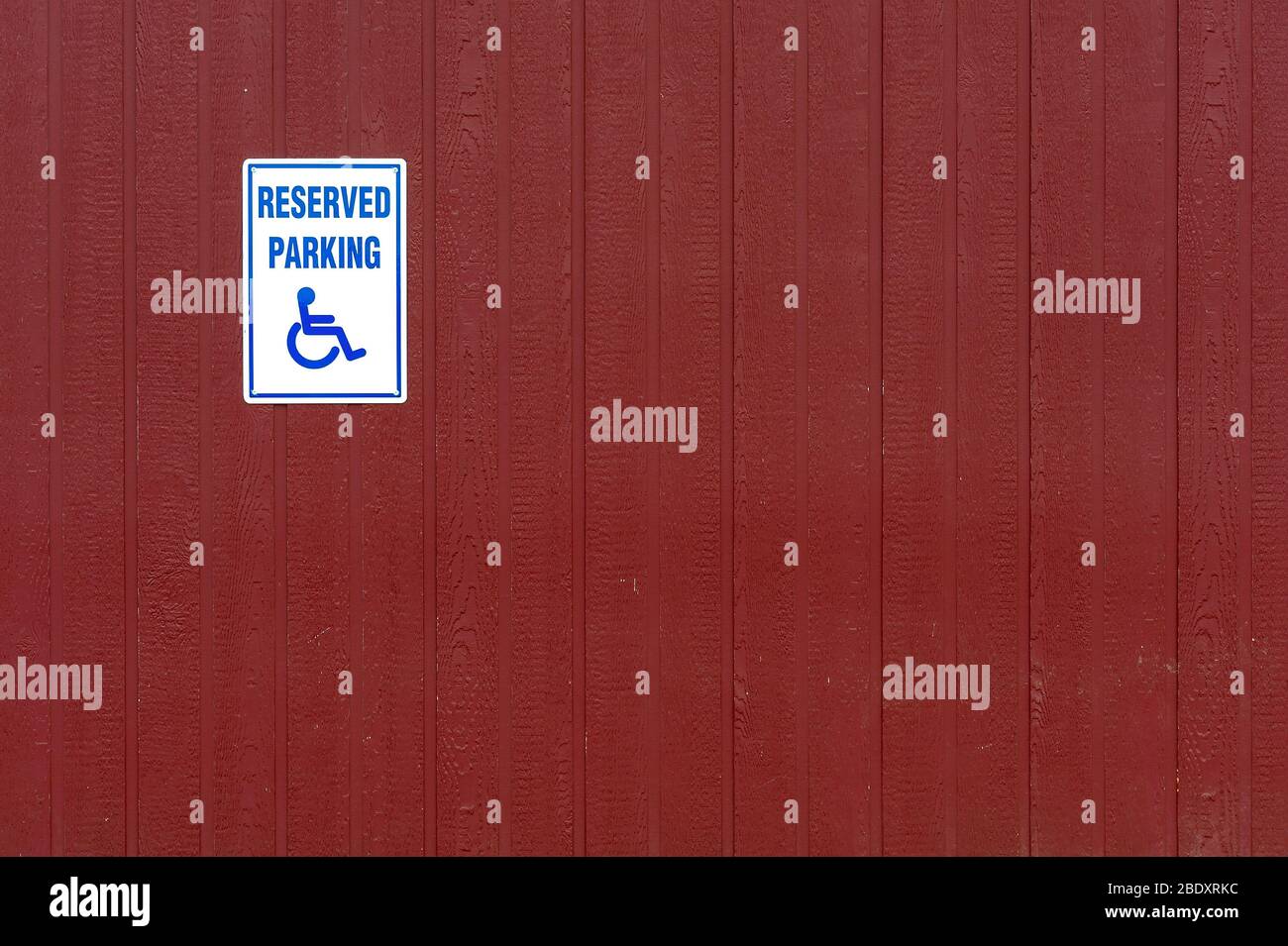 Schild für Behindertenparkplätze an der roten Wand Stockfoto