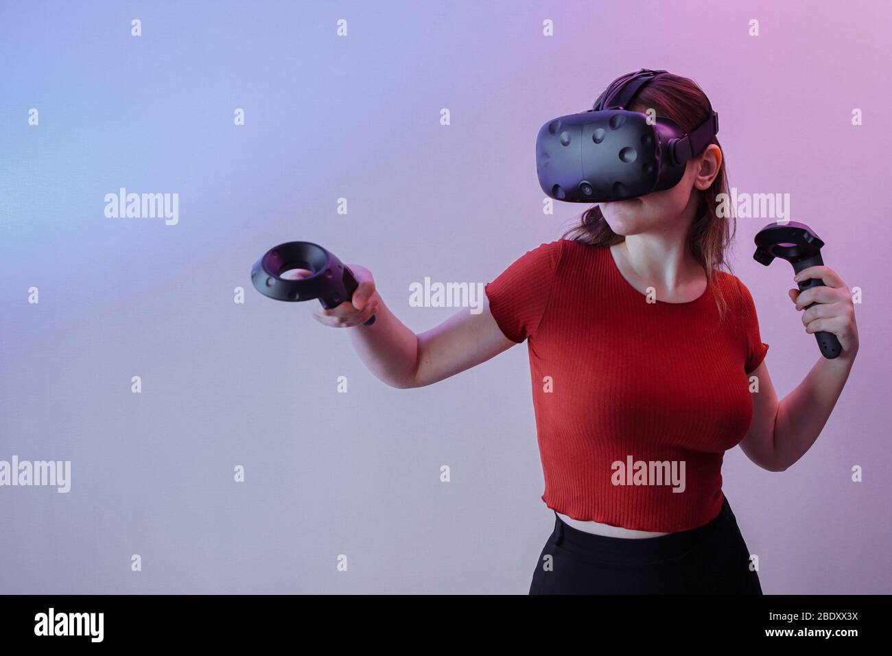 Ein Mädchen ohne Mund in einem roten Pullover und eine gute Figur spielt in Virtual-Reality-Brille. Stockfoto