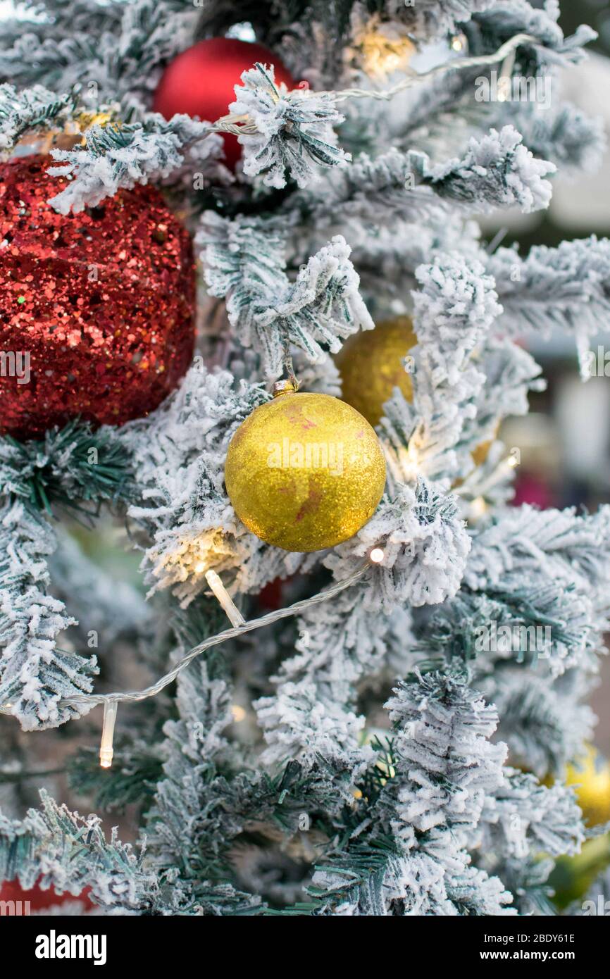 Weihnachten im Hintergrund mit schneebedeckten Ästen mit roten und goldenen Weihnachtskugeln hängen von dem Baum. Stockfoto