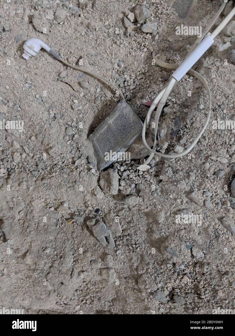 Weiße Kopfhörer oder Kopfsets mit einem iPad beschädigt und vergraben auf den Boden. Staubige Kopfhörer auf dem Boden Stockfoto