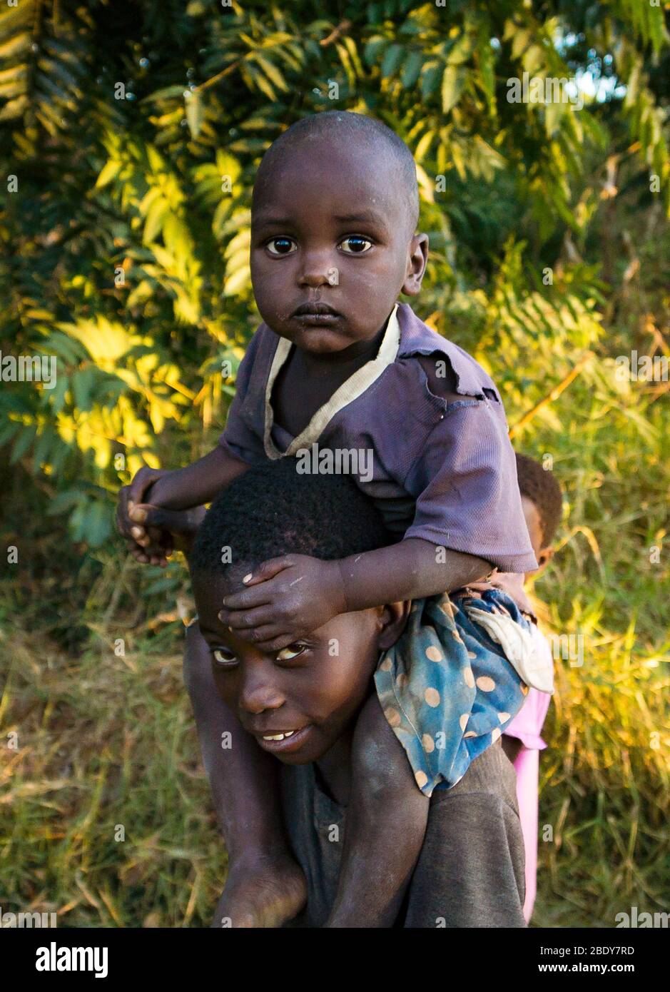 Ein Kleinkind sitzt auf den Schultern seines Bruders im Norden Malawis Stockfoto
