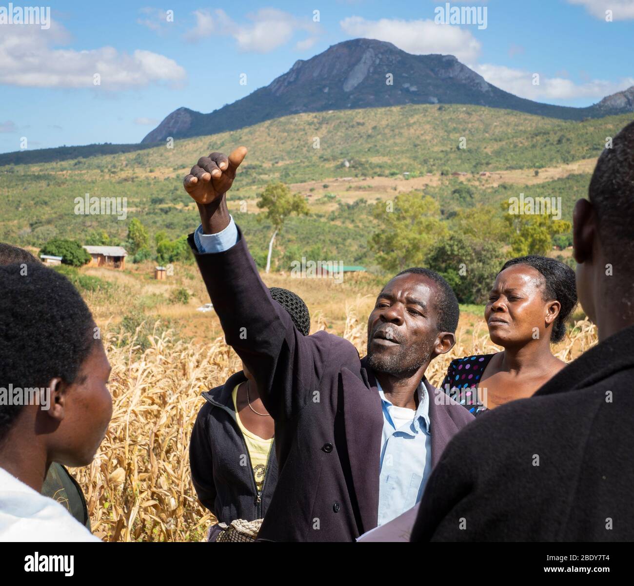 Bauer in Malawi hebt die Hand lebhaft und spricht mit einer Gruppe von Bauern auf dem Feld Stockfoto