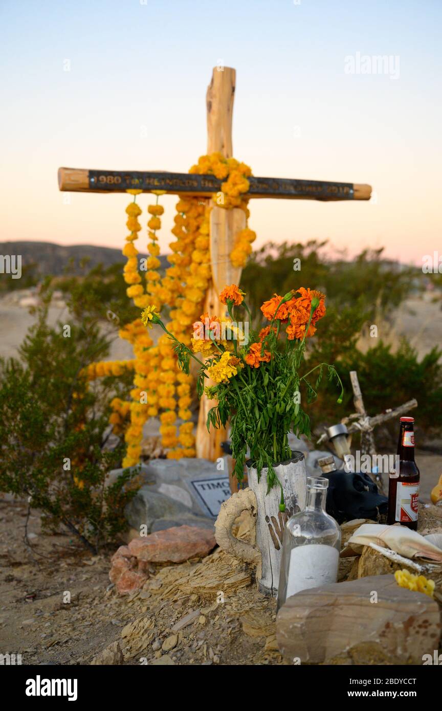 Ein Holzkreuz mit Ringelblumen auf dem Terlingua Cemetery in West Texas, wo die Gräber mit handgefertigten Verzierungen markiert sind. Stockfoto