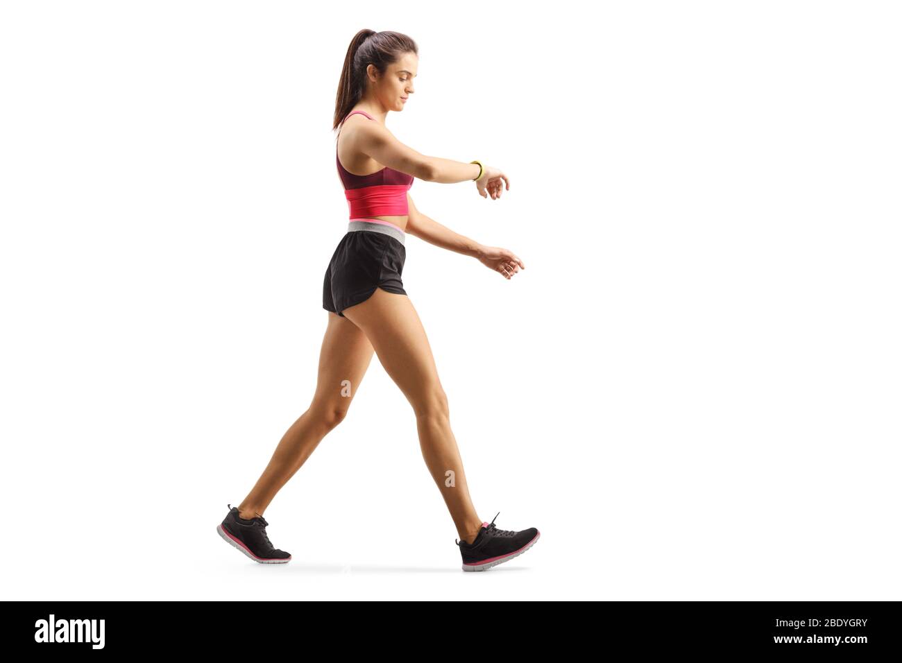 Full length Profil Aufnahme einer fit junge Frau zu Fuß Überprüfung ihrer Sportarm-Band isoliert auf weißem Hintergrund Stockfoto