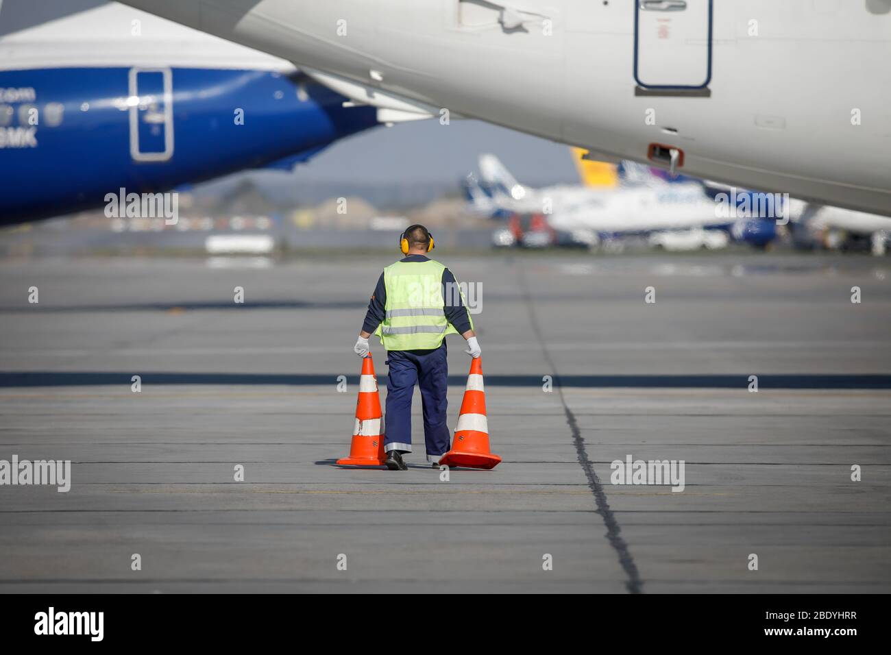 Mann für ein Flughafenpersonal auf der Landebahn zwischen kommerziellen Flugzeugen. Stockfoto