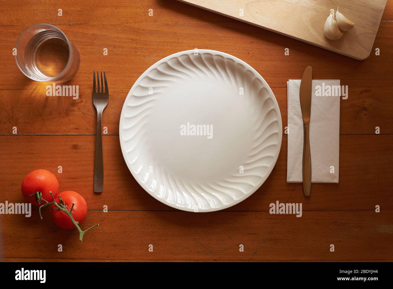 Porzellanteller und Besteck auf Holzhintergrund mit mediterranen Elementen Stockfoto