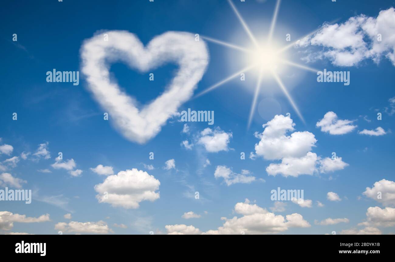 Herzförmige Wolke vor einem sonnigen und blauen Himmel Hintergrund. Liebe ist in der Luft Konzept. Stockfoto