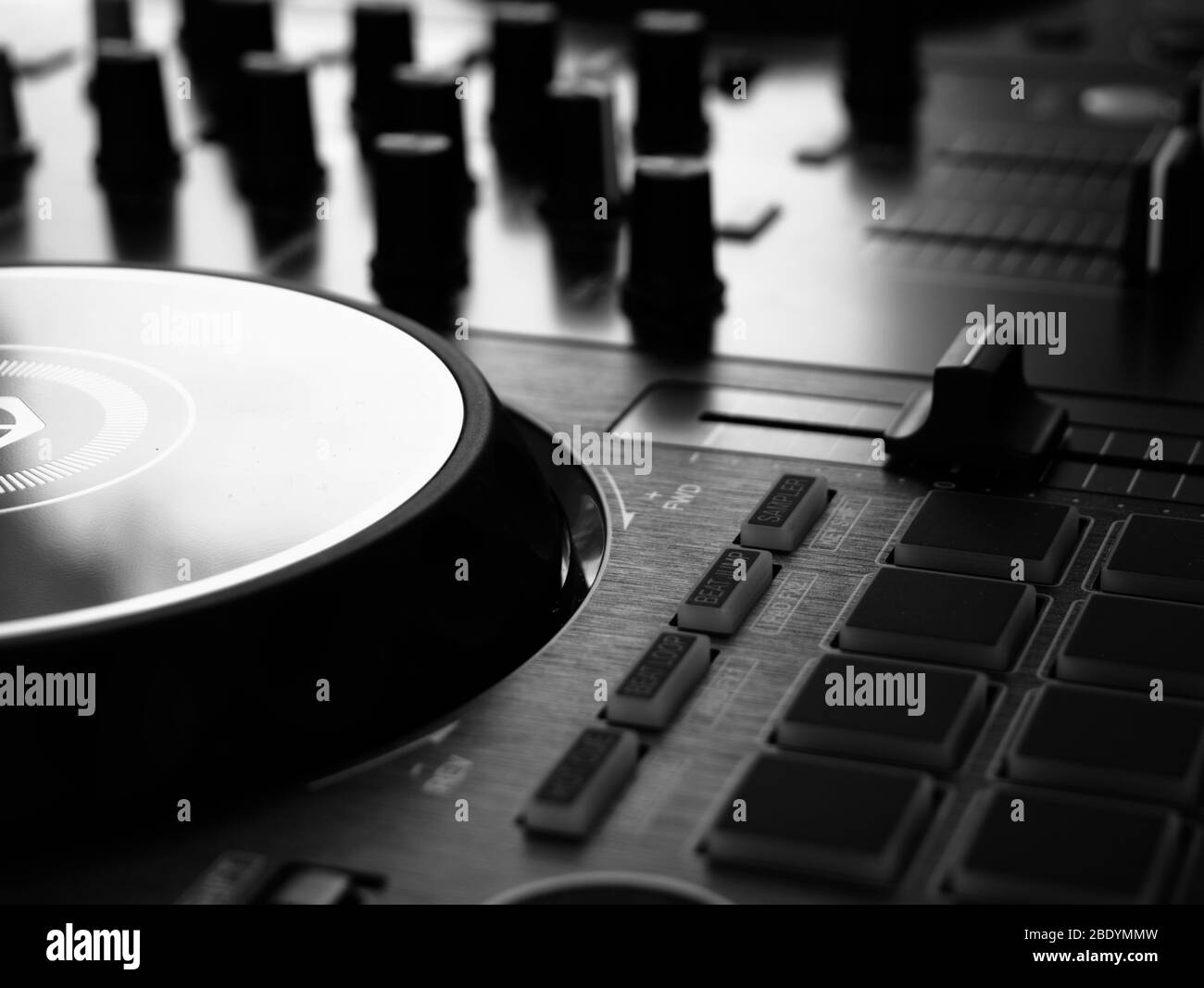 Nahaufnahme eines DJ-Controllers, der einen Teil des linken Player-Bereichs und den Mixer-Bereich außerhalb des Fokus im Hintergrund zeigt Stockfoto