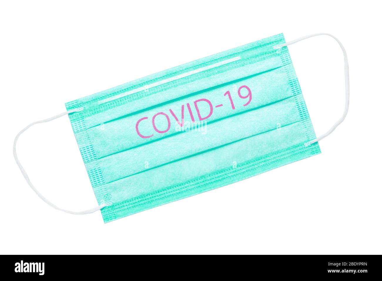Grüne medizinische Maske auf weißem Hintergrund isoliert. COVID-19 Inschrift auf der Maske, die die weltweite Coronavirus-Pandemie symbolisiert Stockfoto