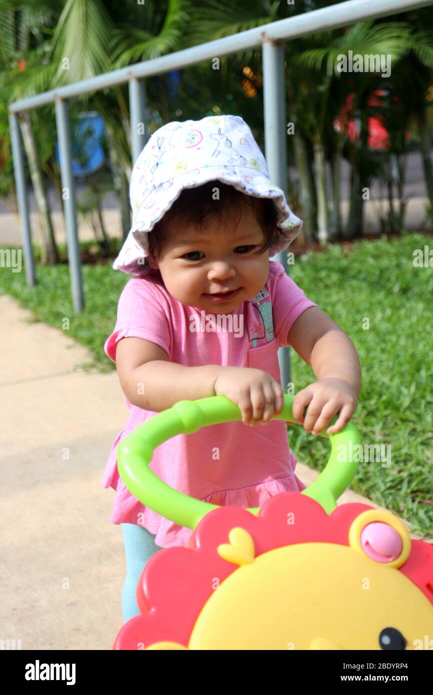 1 Jahr altes Mädchen, Kleinkind, Gesicht asiatischen Baby, spielen in der Stadt Spielplatz spielen Park, öffentlichen Raum mit ihrem Baby Push Walker Stockfoto