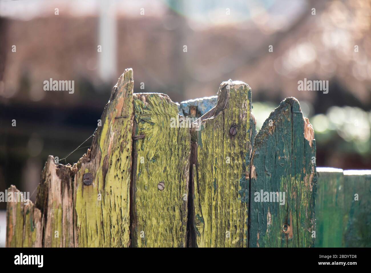 Detail des alten genagelten rostigen Holzzauns mit grüner Farbe abblätternd Stockfoto