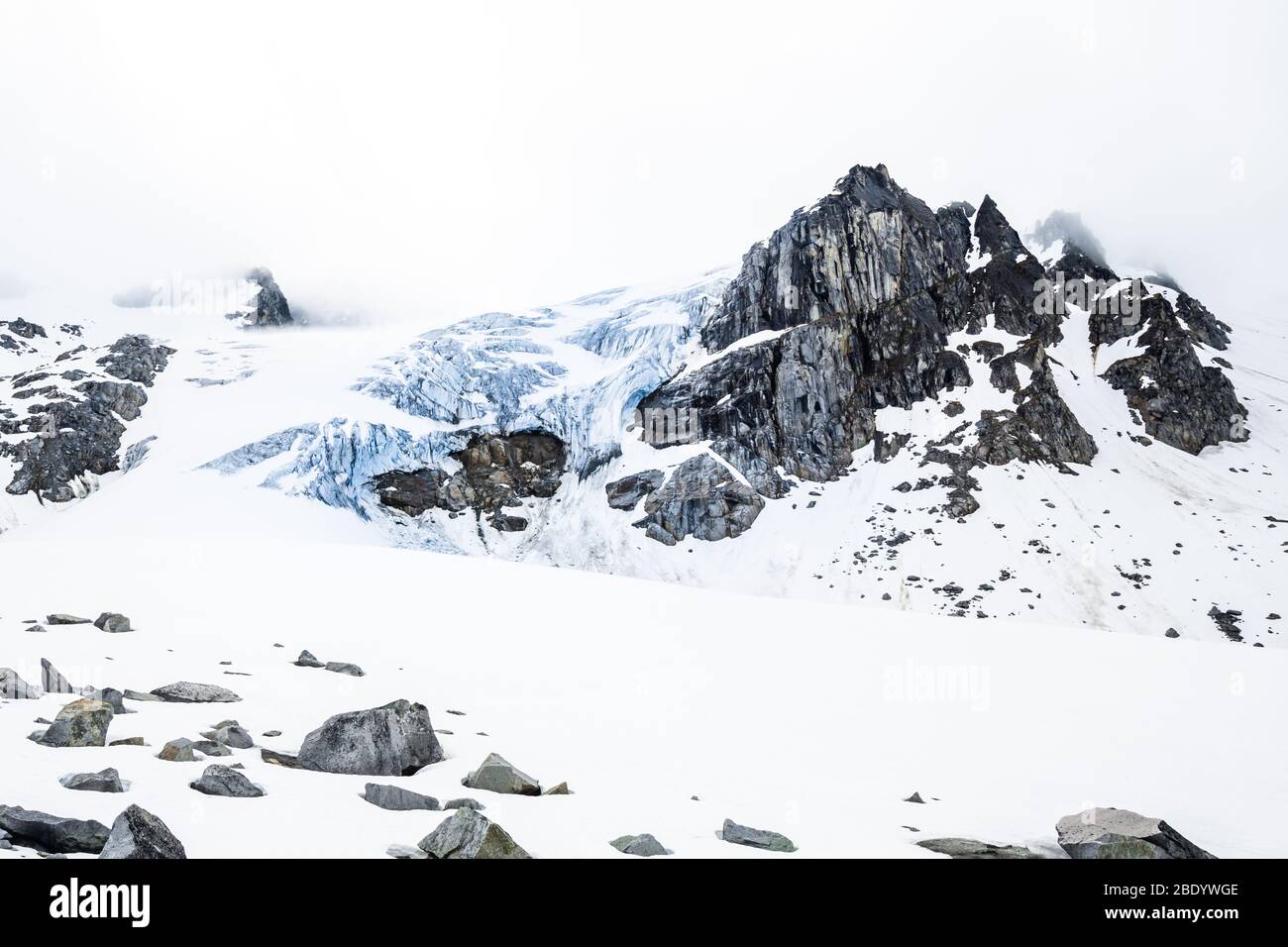 Zerklüftete blaue Eisfläche eines Gletschers unter schmelzendem Schnee auf dem Montana Peak im Frühjahr. Tief in der Wildnis des Hinterlandes der Talkeetna Bergkette Alaskas. Stockfoto