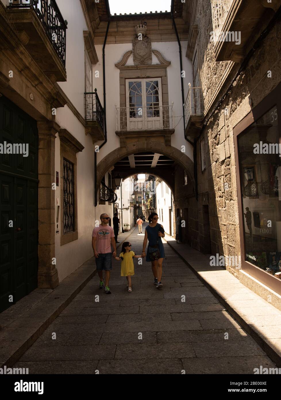 Menschen, die in alten engen Straßen mit hohen terrassierten mittelalterlichen Häusern und Torbogen in der historischen Altstadt von Guimaraes Nord-Portugal Europa Stockfoto