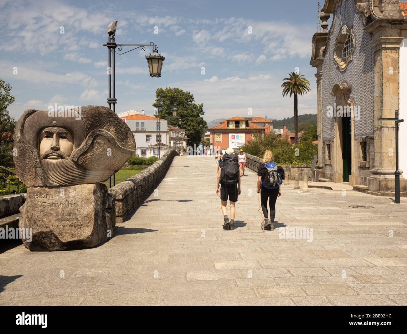 Zwei Wanderinnen auf der zentralen Route Camino Portugués, vorbei an einer großen Willkommensstatue Bom Camino bei Ponte de Lima in Nordportugal Stockfoto