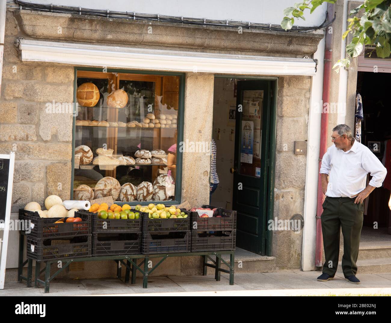 Straßenszene mit einem Mann vor einem Geschäft, das Obst und traditionelles Brot in Ponte de Lima Nord Portugal verkauft Stockfoto