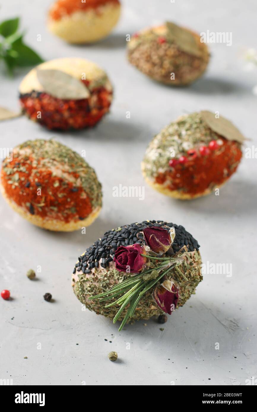 Öko-Design von Ostereiern mit verschiedenen Gewürzen und Getreide, ohne Farb- und Konservierungsstoffe auf grauem Betongrund, Vertikal-Format Stockfoto