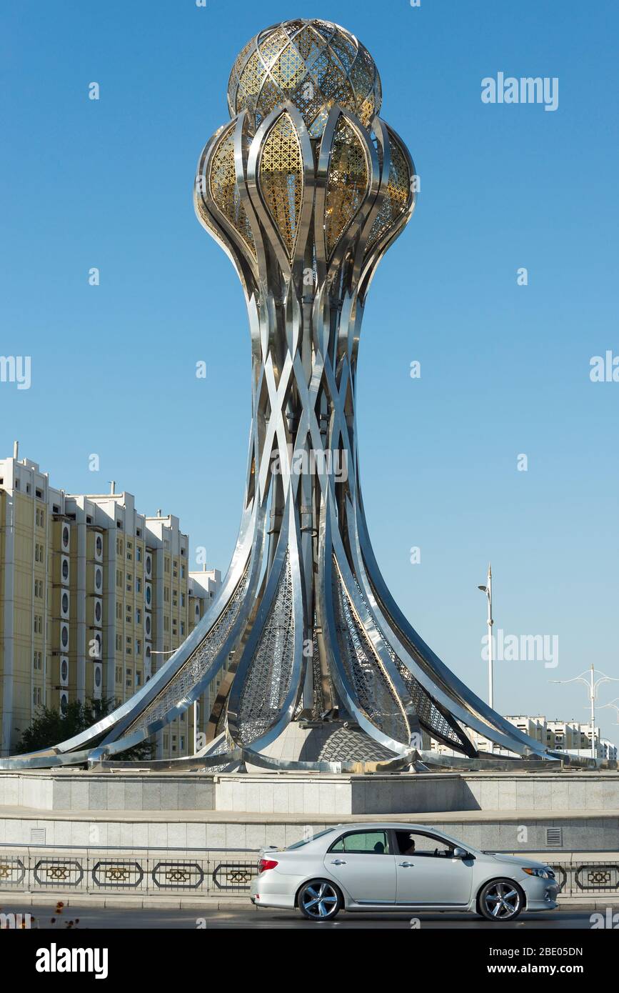 Das Denkmal und das Auto von Zemin in Aschgabat, Turkmenistan. Glänzendes metallisches Denkmal in Gold und Silber. Auch bekannt als das Erddenkmal. Stockfoto
