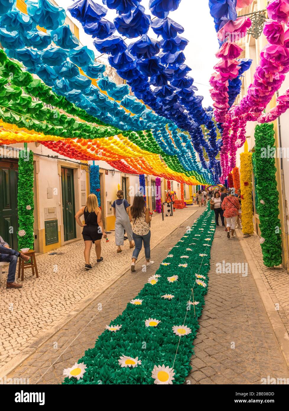 Leute, die während des traditionellen Festa dos Tabuleiros (Festival der Trays) eine sehr schön eingerichtete Straße in Tomar entlang laufen. Portugal Stockfoto