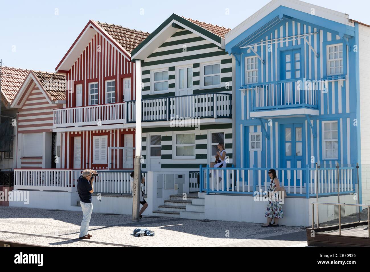 Fotograf fotografiert Mädchen posiert von den bunten gestreiften Häusern an der Costa Nova do Prado in der Nähe von Aveiro Portugal. Stockfoto