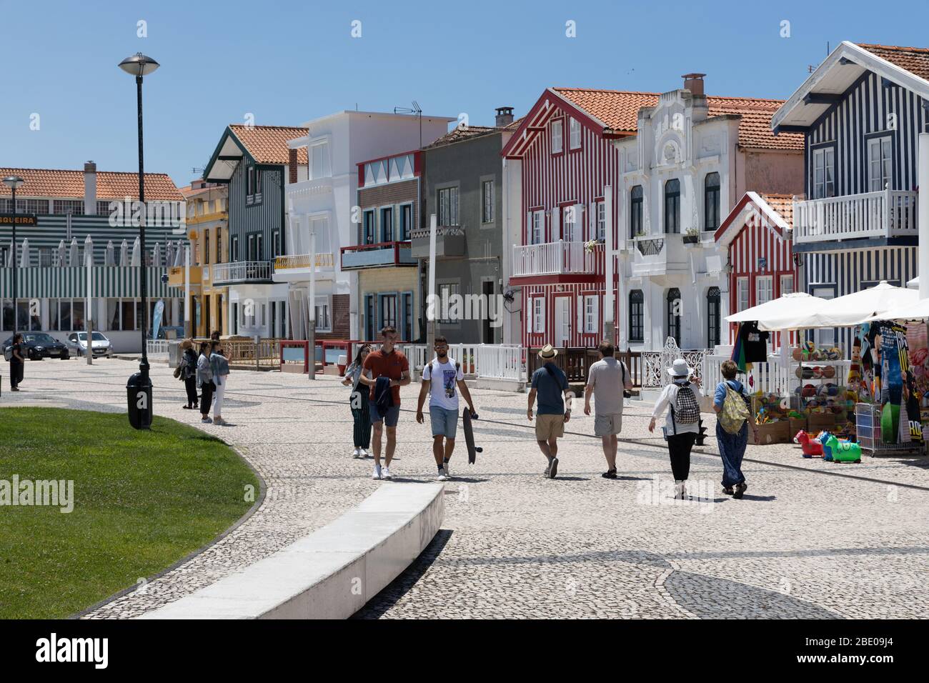 Touristen, die auf der Promenade an farbenfroh gestreiften Gebäuden an der Costa Nova do Prado Ilhavo in der Nähe von Aveiro Portugal vorbeigehen. Stockfoto