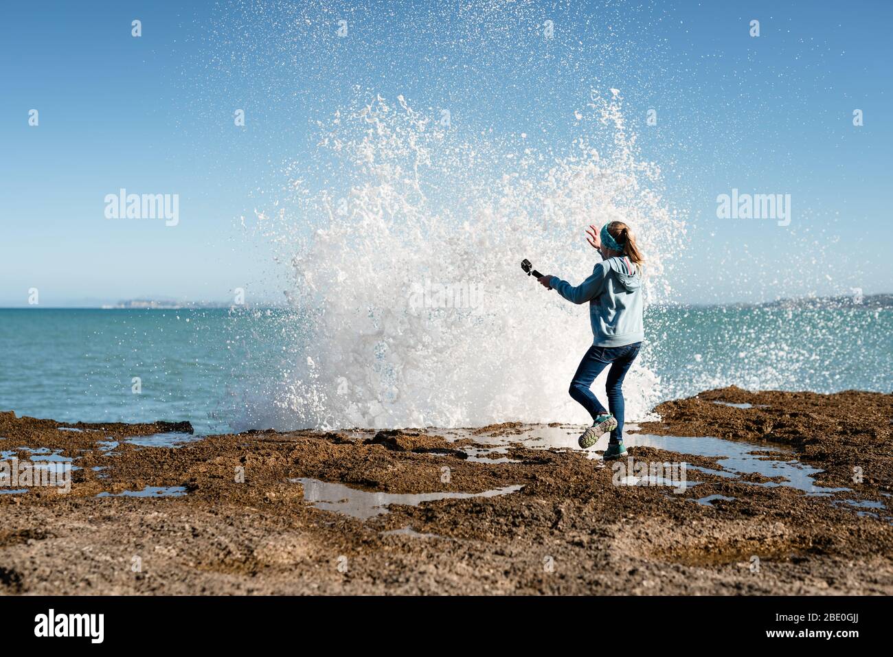 Tween erschreckt durch Welle, die über Felsen krachte Stockfoto