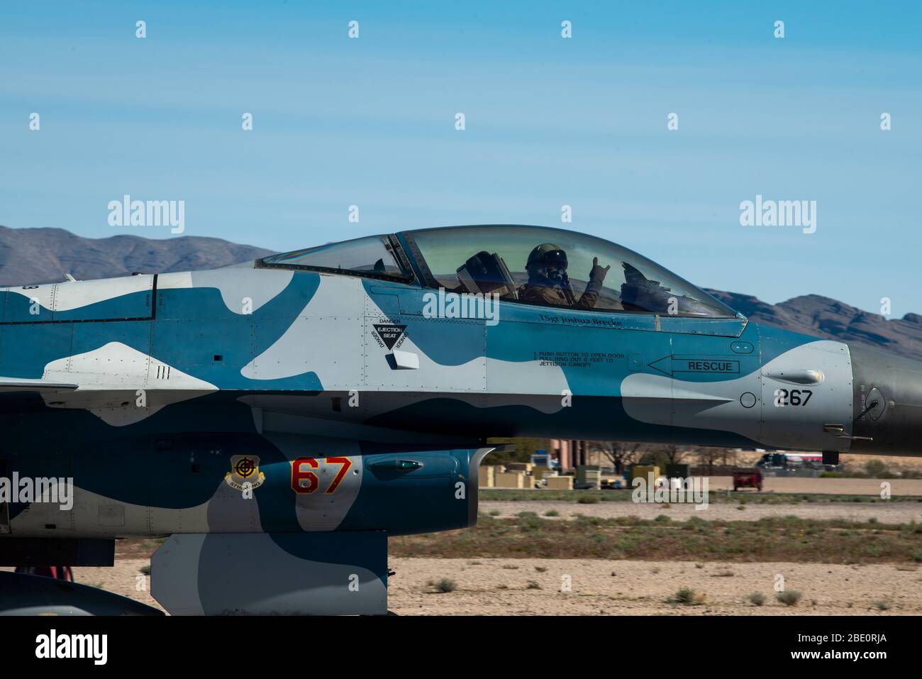 Ein F-16 Fighting Falcon Kampfjet Pilot, der dem 64. Aggressor Squadron (AGRS) zugewiesen wurde, wirft ein Moralzeichen vor dem Start in der Nellis Air Force, Nevada, 3. April 2020. Die 64. AGRS flog blaue F-16, um medizinisches Personal und Ersthelfer aus dem Las Vegas Valley sowie im ganzen Land zu ehren, während sie eine Trainingsmission durchführten. (USA Luftwaffe Foto von Staff Sgt. Tabatha Arellano) Stockfoto