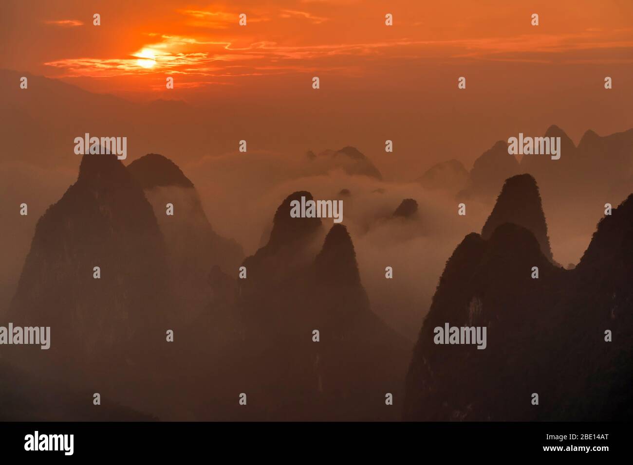 Dramatischer Sonnenaufgang über dem Nebel gehüllten Kalksteingipfel von Guilin. Stockfoto