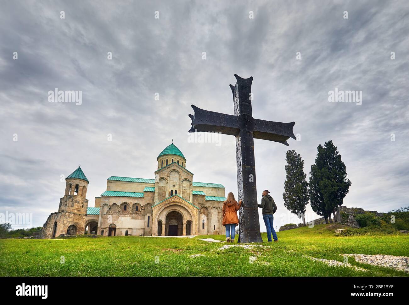 Touristische Paar in der Nähe von grossen Kreuz vor bagrati Kirche bei bedecktem Himmel in Kutaissi, Georgien Stockfoto