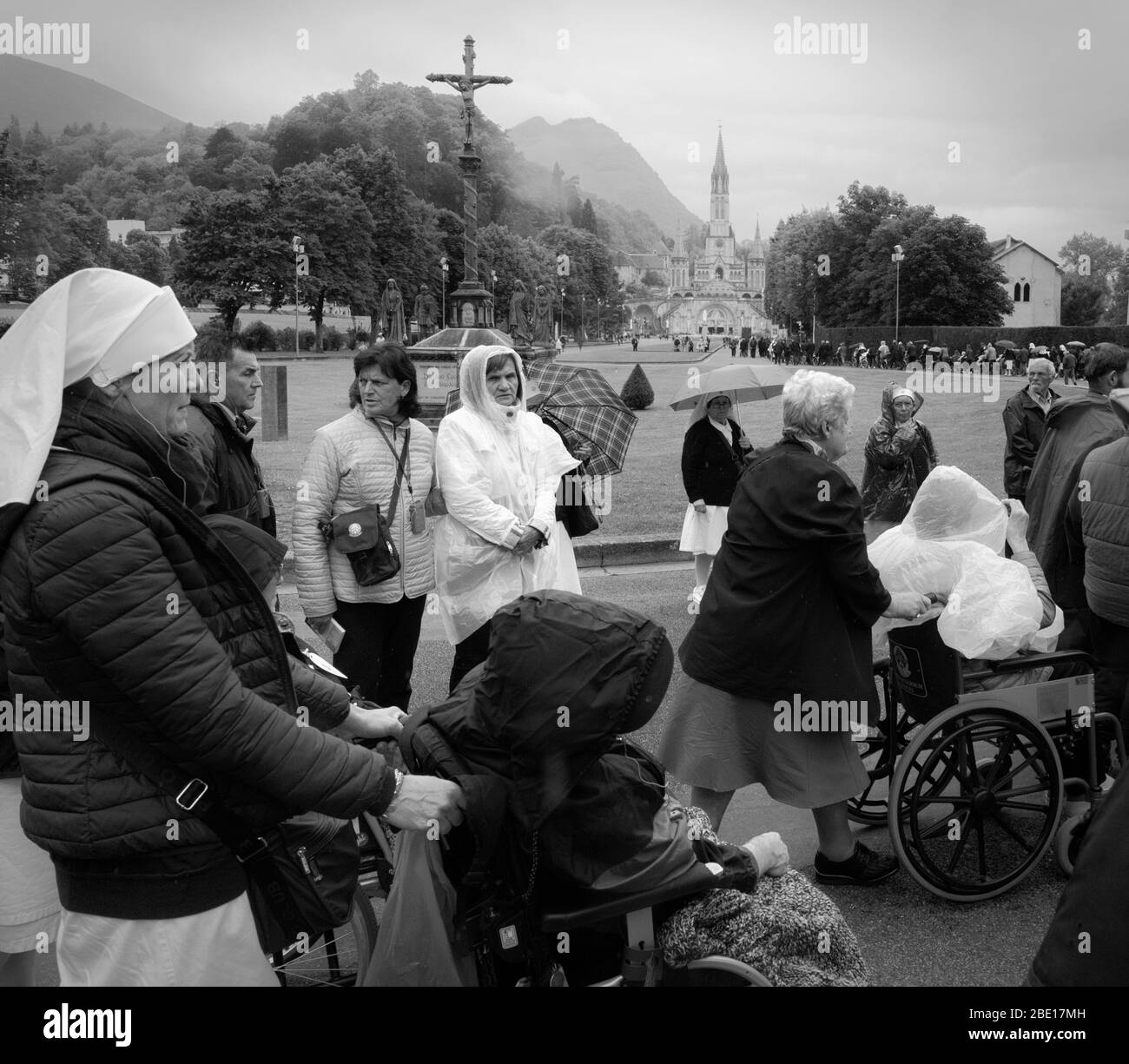 Menschen im Rollstuhl, die zum Heiligtum unserer Lieben Frau von Lourdes in der Hoffnung auf Trost oder Heilung ihrer Krankheiten, Lourdes, Hautes-Pyrénées gerollt werden Stockfoto