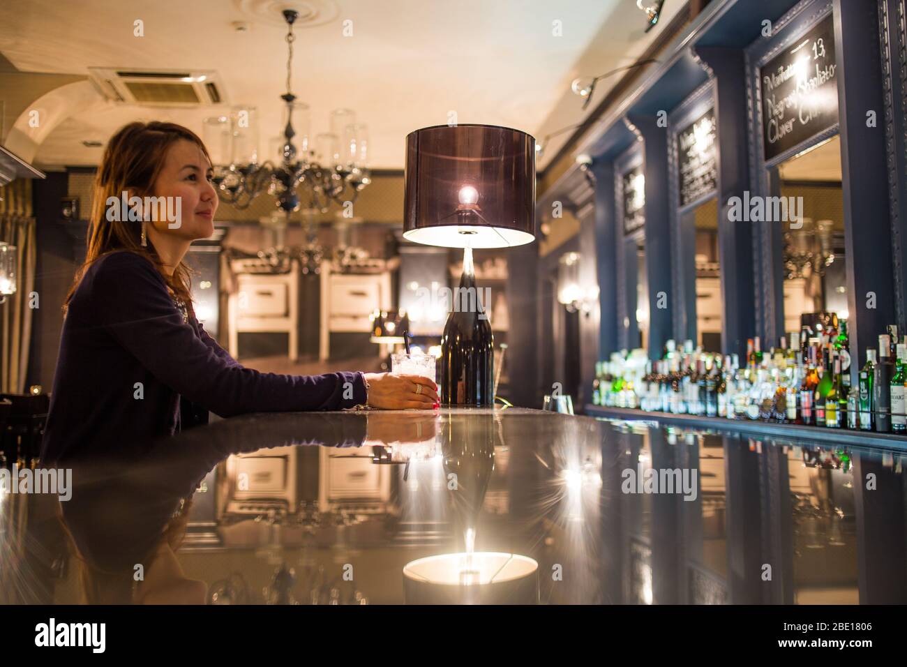 Eine asiatische Einzeltouristin hält für einen Drink an der Cocktailbar des Grand Cafe in Minsk, Weißrussland. Stockfoto