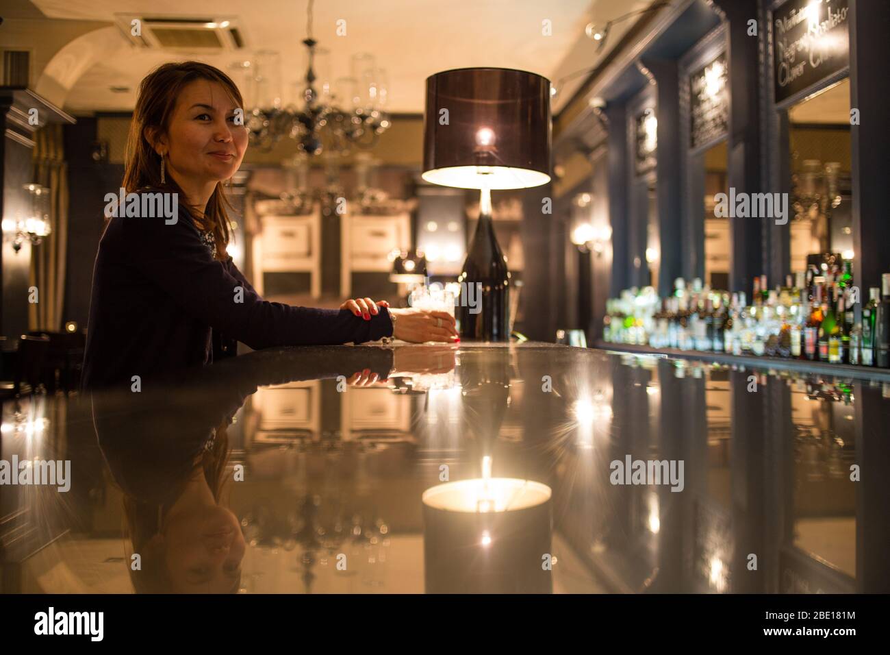 Eine asiatische Einzeltouristin hält für einen Drink an der Cocktailbar des Grand Cafe in Minsk, Weißrussland. Stockfoto