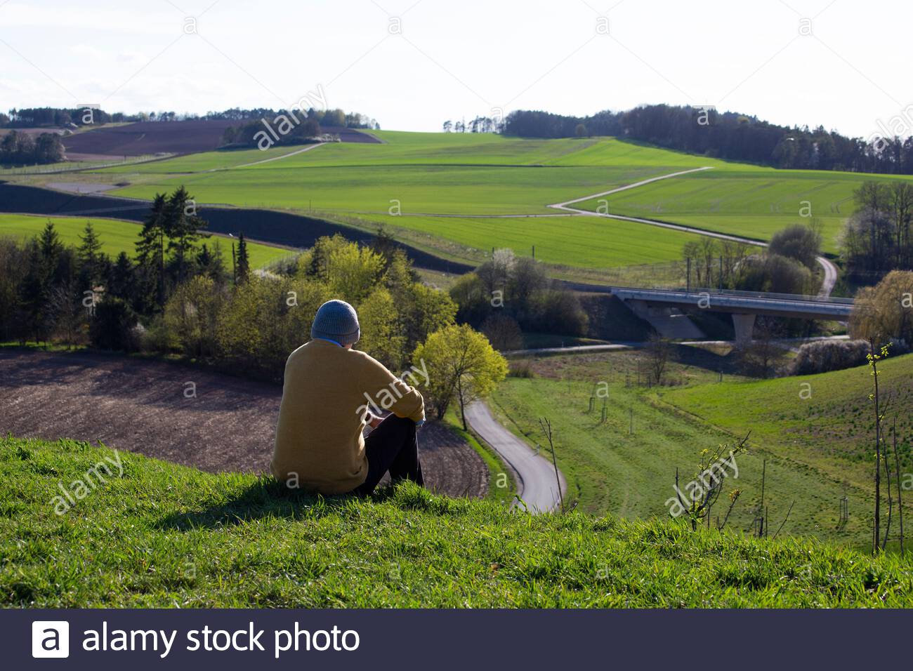 Ein Mann genießt eine schöne Aussicht an einem schönen Tag in Bayern, wo die soziale Distanz wegen des Corona-Virus weiter anhält. Stockfoto