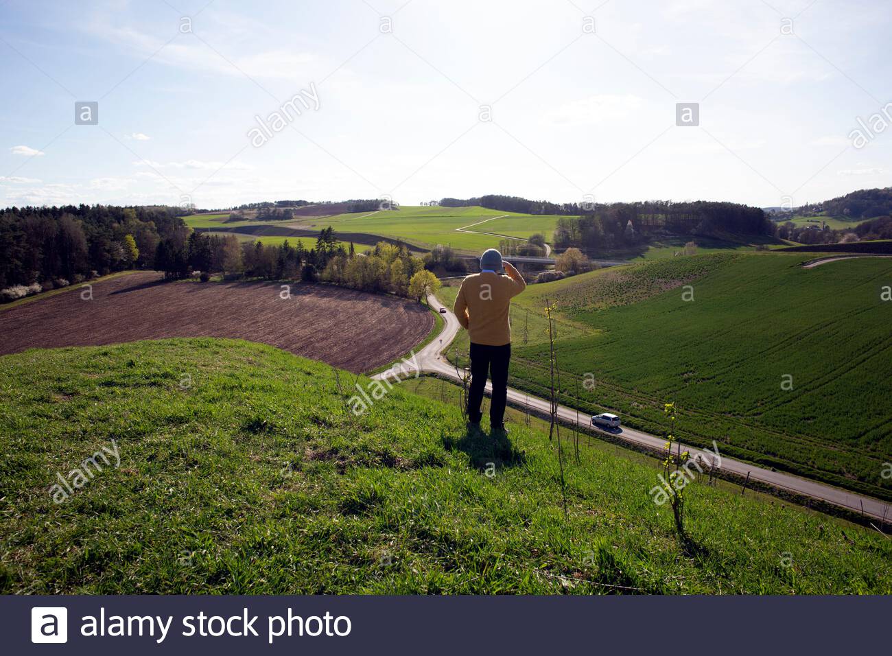 Ein Mann genießt eine schöne Aussicht an einem schönen Tag in Bayern, wo die soziale Distanz wegen des Corona-Virus weiter anhält. Stockfoto