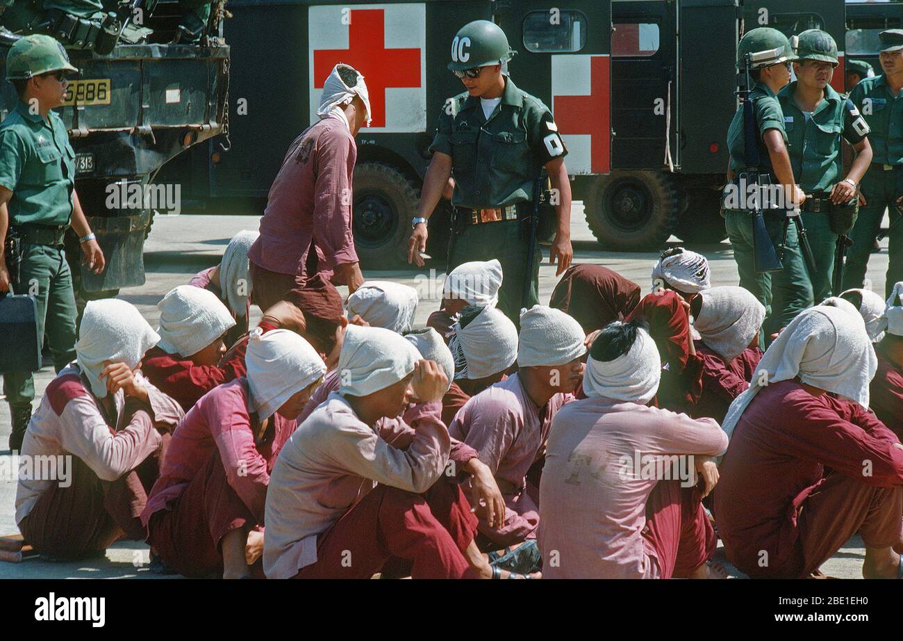 Viet Cong Kriegsgefangenen sitzen auf der Rampe bei Tan Son Nhut Air Base unter den wachsamen Augen der Südvietnamesischen Militärpolizei. Die Kriegsgefangenen zu Loc Ninh, Südvietnam für die Gefangenen Austausch zwischen den Vereinigten Staaten und Nord/Süd Vietnam Vietnam/Viet Cong Militär eingeflogen werden. Stockfoto