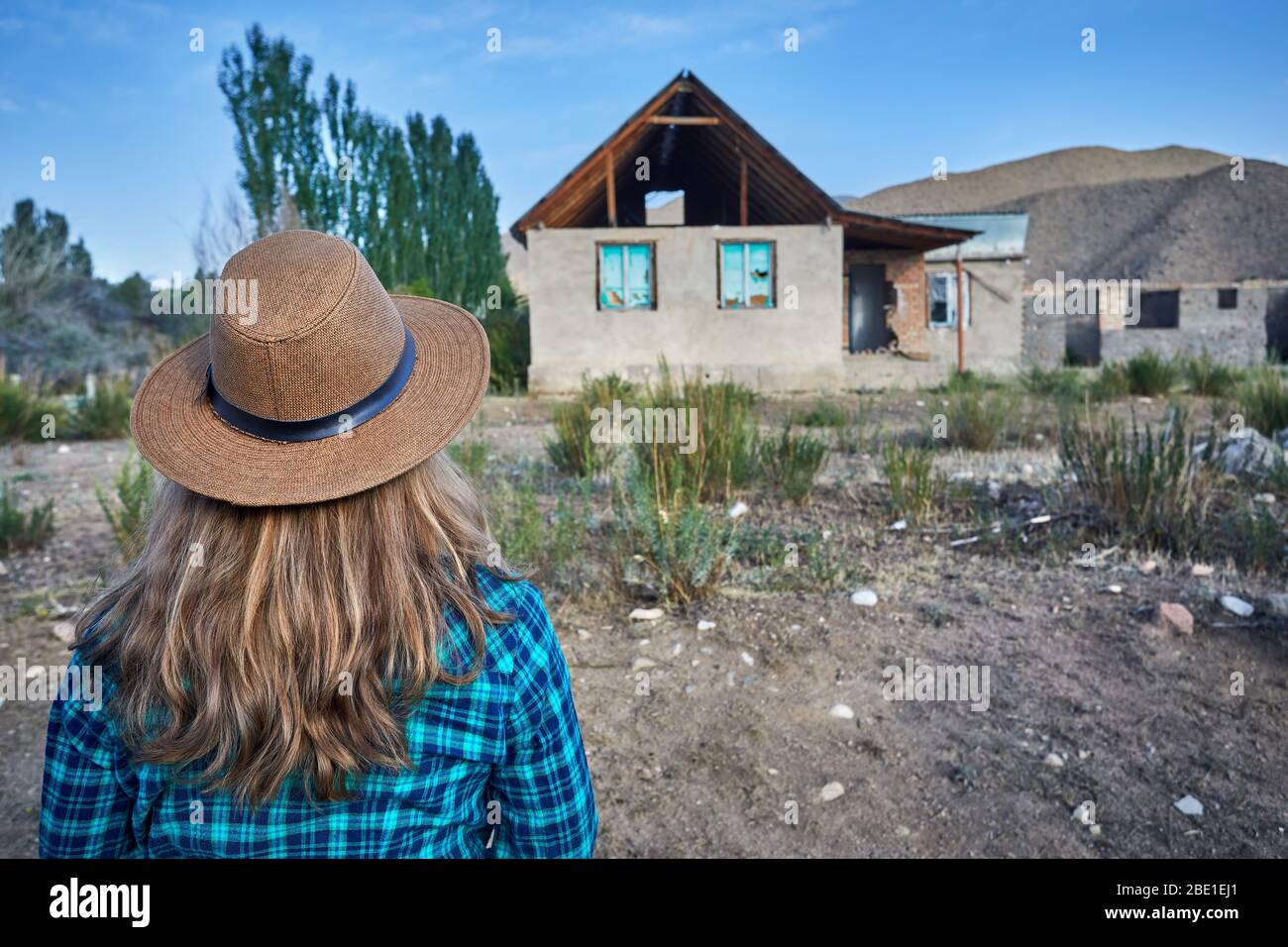 Frau mit Hut und kariertes Hemd auf ruiniert altes Haus im Dorf Stockfoto