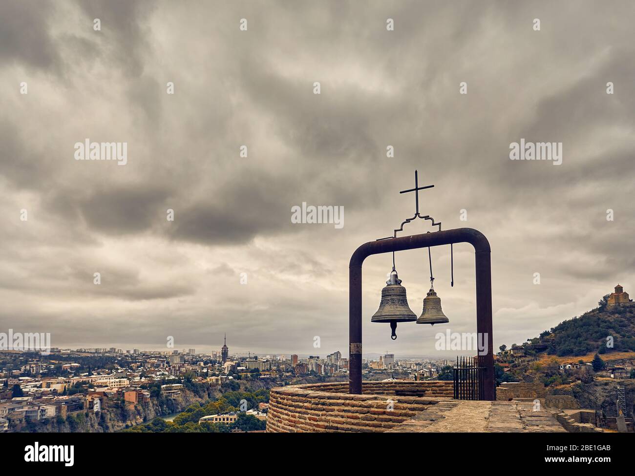 Alte mittelalterliche Festung Narikala mit großen Glocken an der Wand bedeckt bewölkten Himmel in Tiflis, Georgien Stockfoto