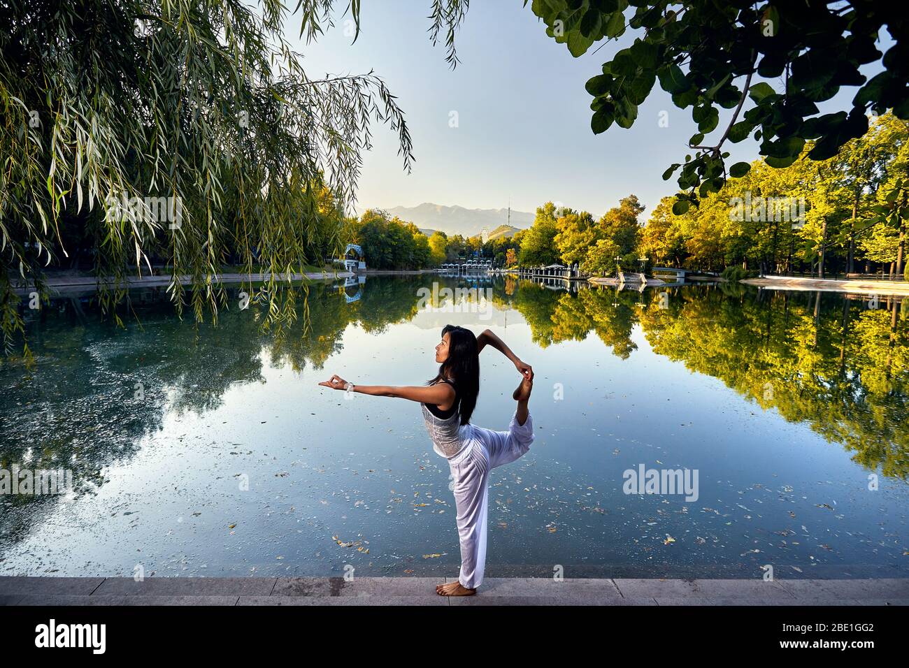 Schöne asiatische Mädchen in weißen Kostüm Yoga in der Nähe des Sees im Park am Morgen Stockfoto