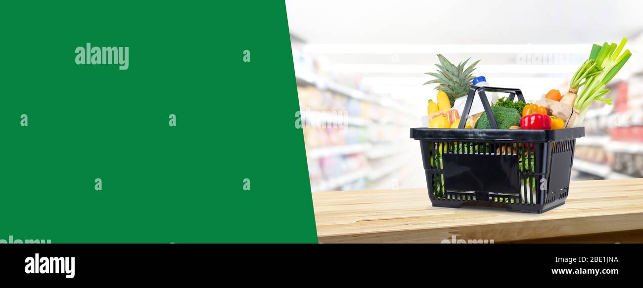 Warenkorb voll von Lebensmitteln auf Holztheke im Supermarkt Hintergrund Banner mit Kopierplatz für Text Stockfoto