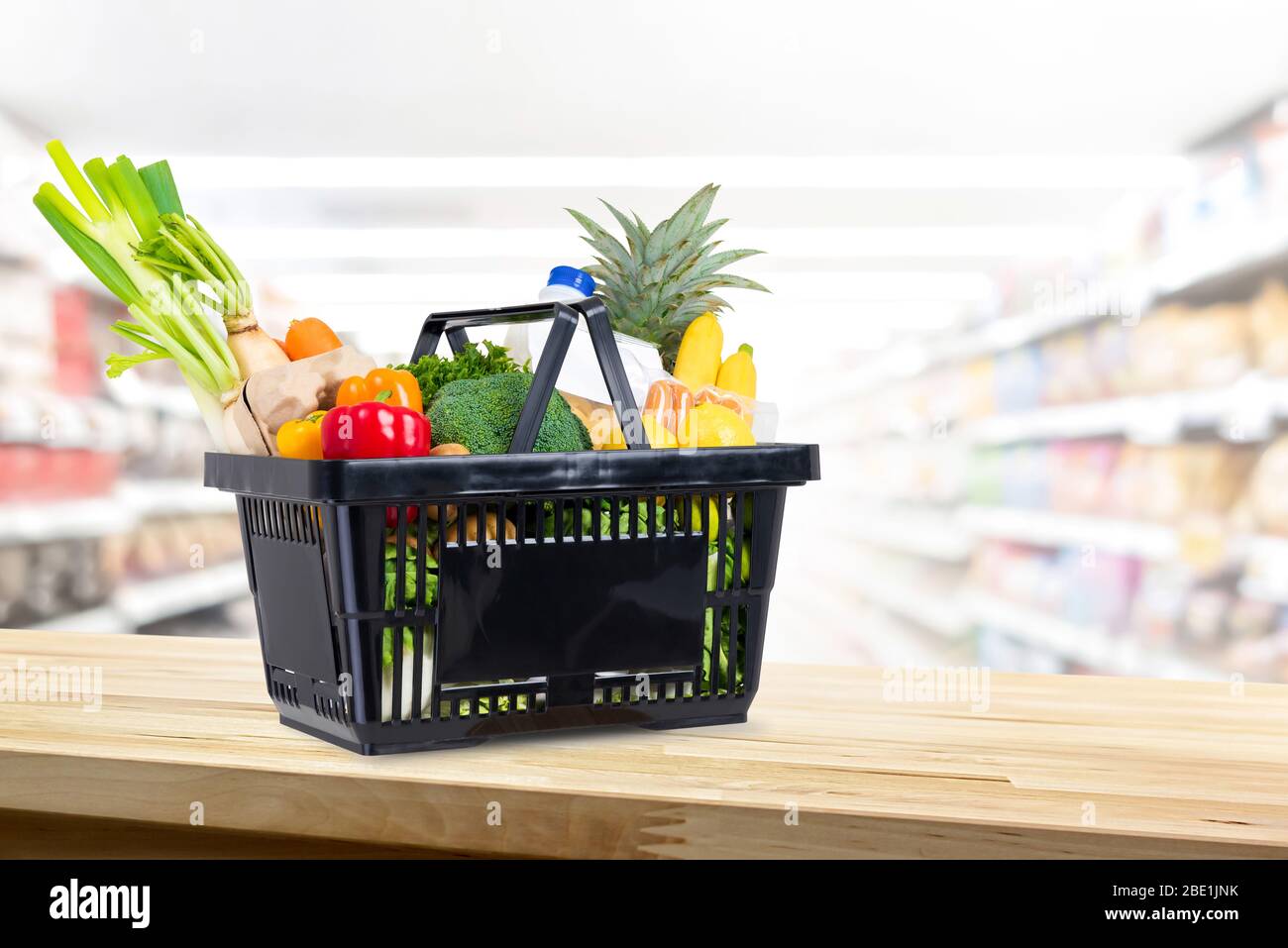 Einkaufskorb voller Lebensmittel auf Holztheke im Supermarkt Hintergrund Stockfoto