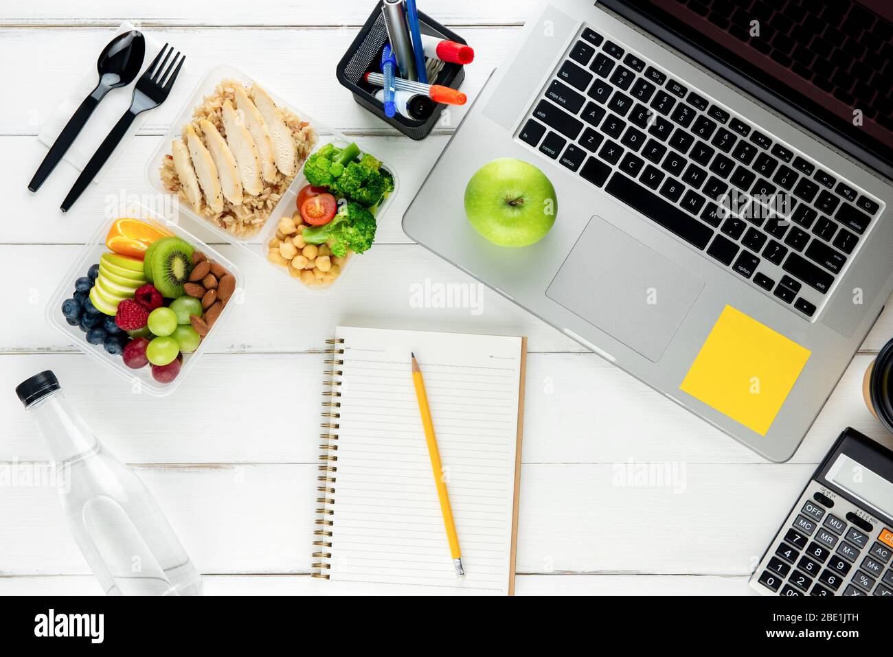 Nehmen Sie nährstoffreiche Lebensmittel mit Laptop-Computer und Ausrüstung auf dem Tisch für die Arbeit von zu Hause aus vorbereitet Stockfoto